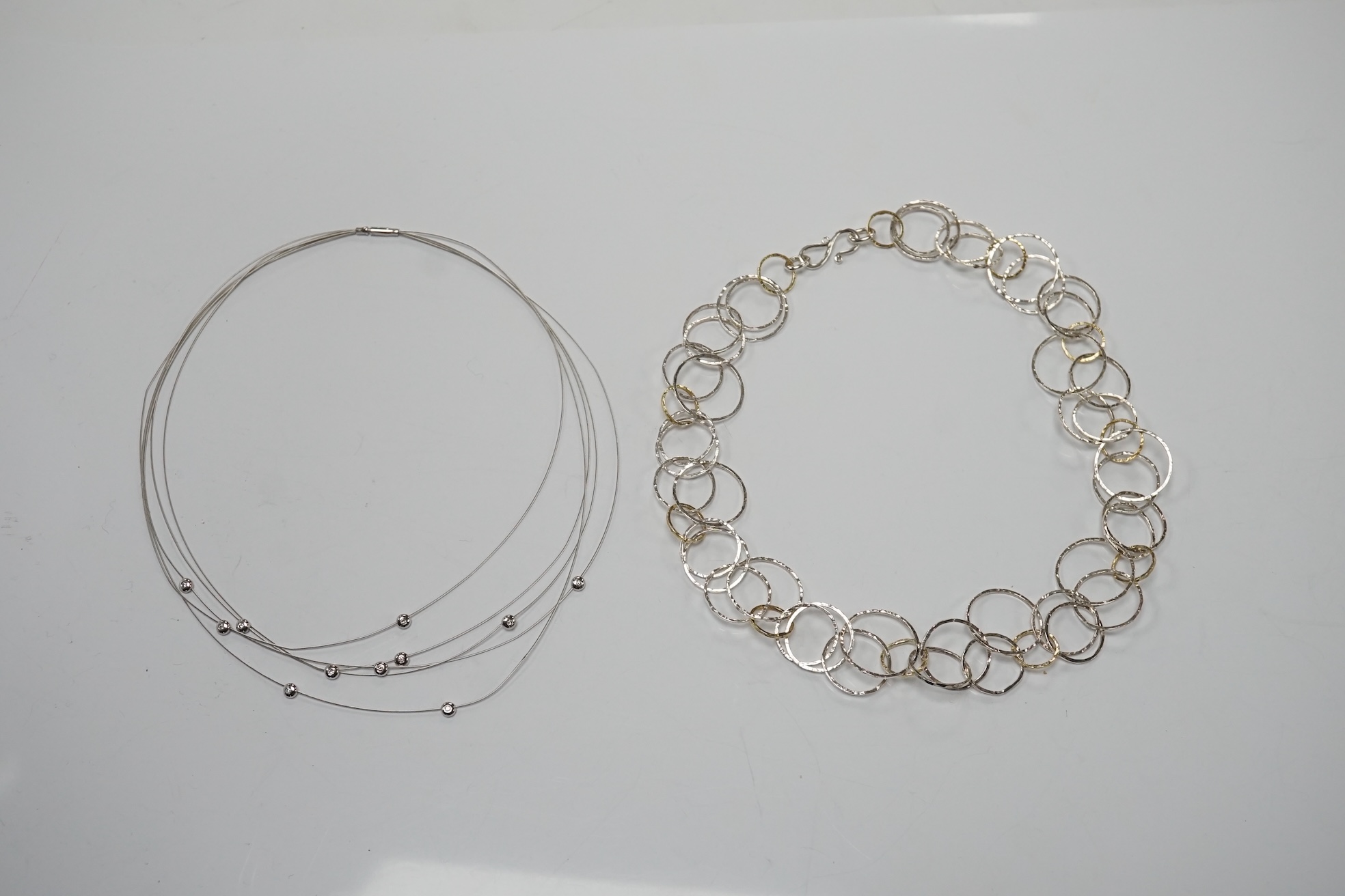A modern Pruden & Smith silver and yellow metal hoop necklace and a 750 white metal and diamond set multi strand necklet retailed by Mappin & Webb. Condition - fair to good